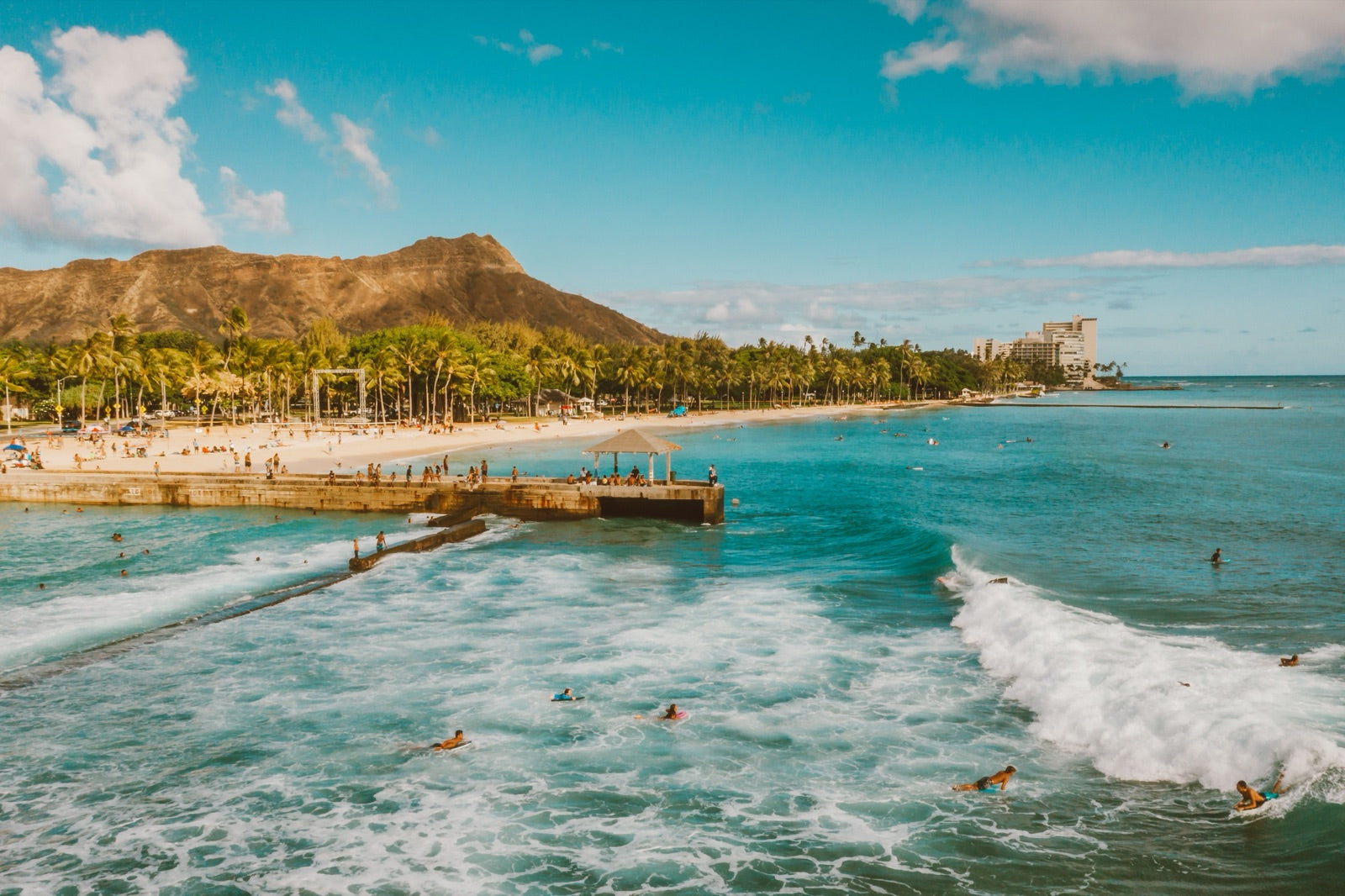 Surfers riding waves at Waikiki Beach with Diamond Head behind
